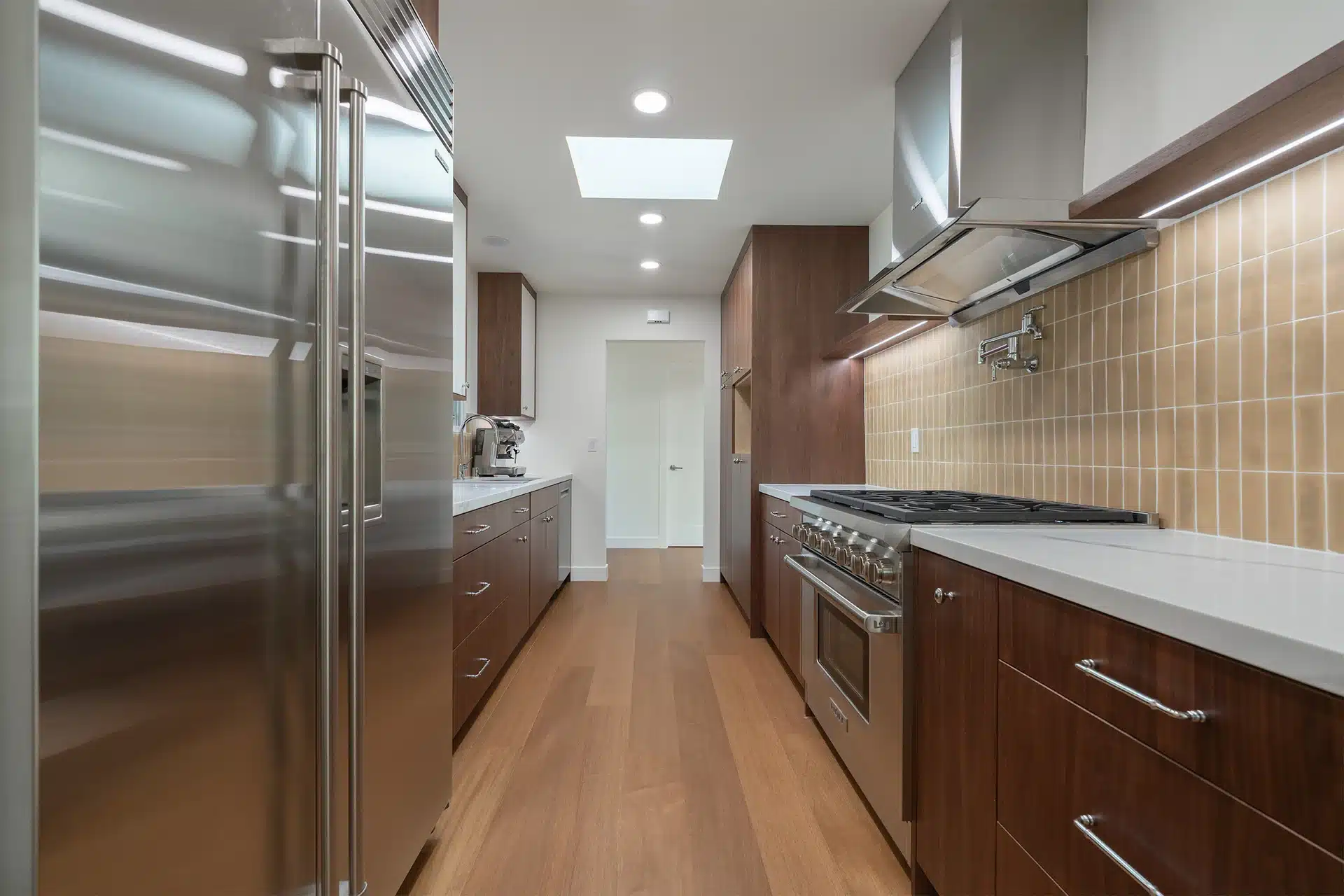 Walnut galley kitchen with tan stack tile, a professional range and a skylight