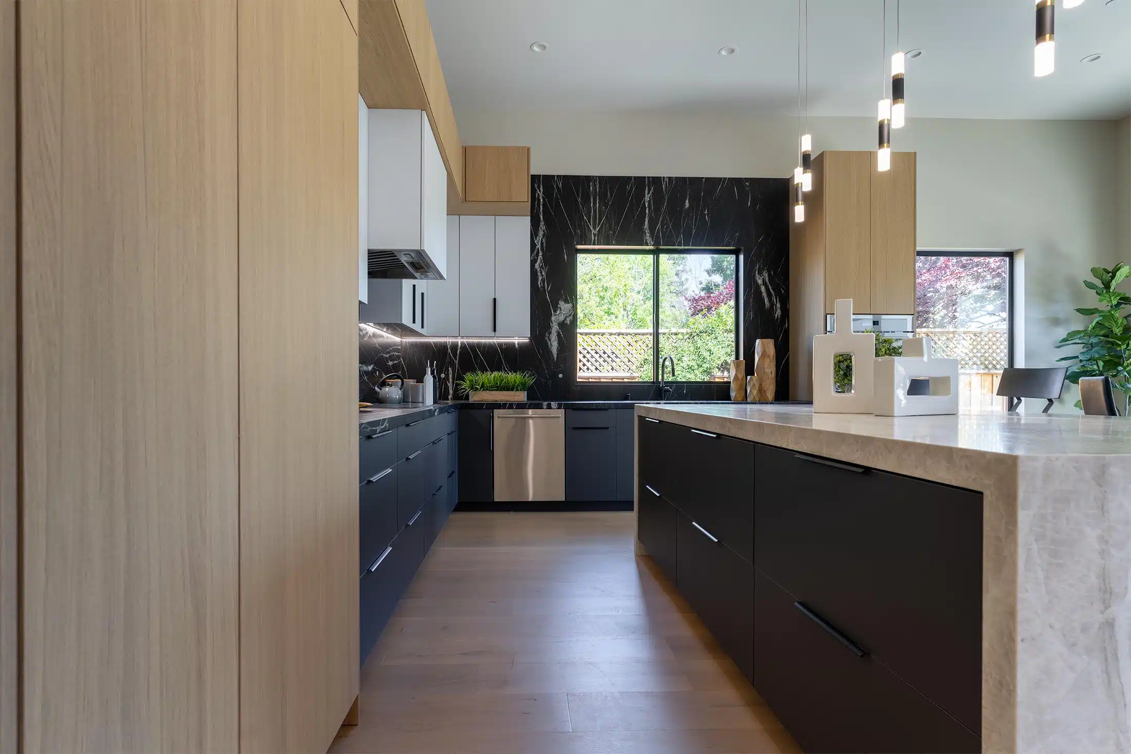 Oak pantry wall opening to navy cabinets and a black marble backsplash